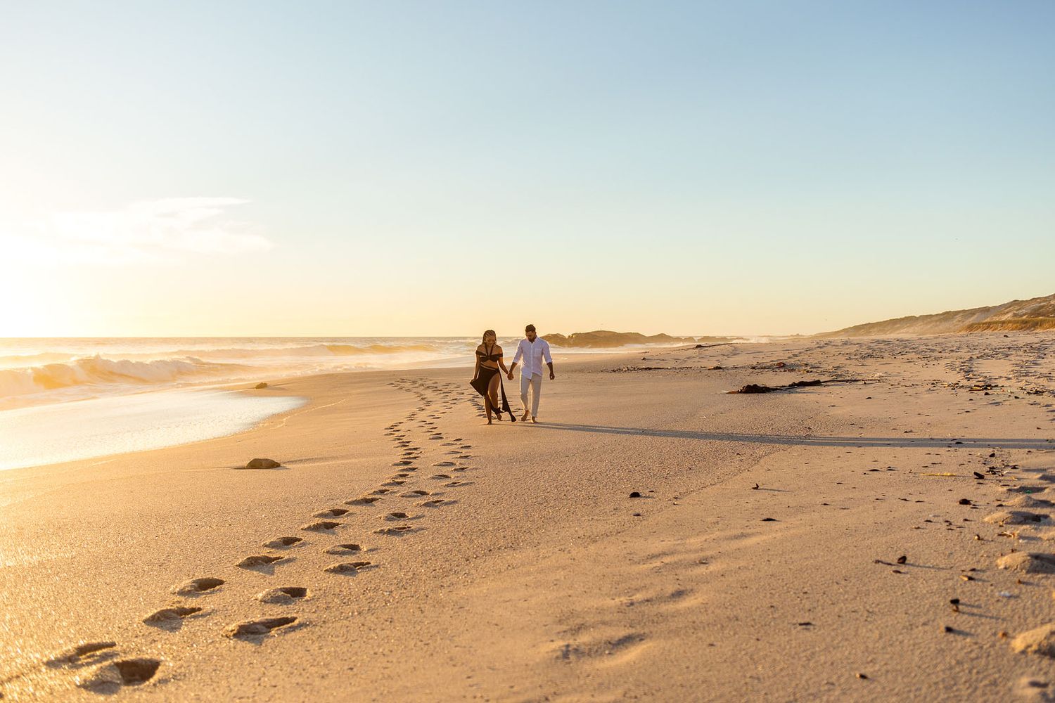 Couple walking on beach, holding hands at golden hour, Melbourne