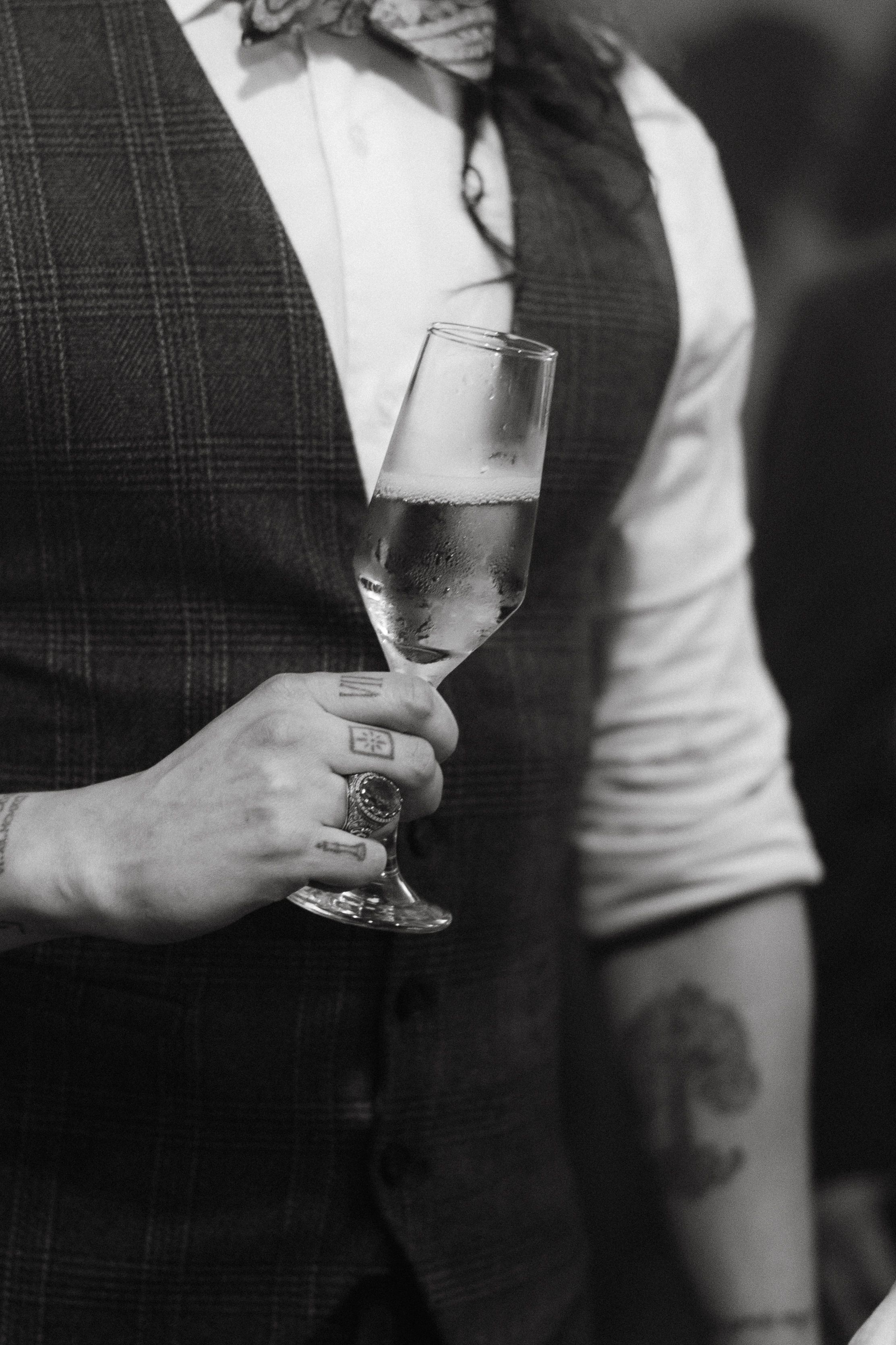 Black and white image showing hands holding champagne glasses at a formal event.