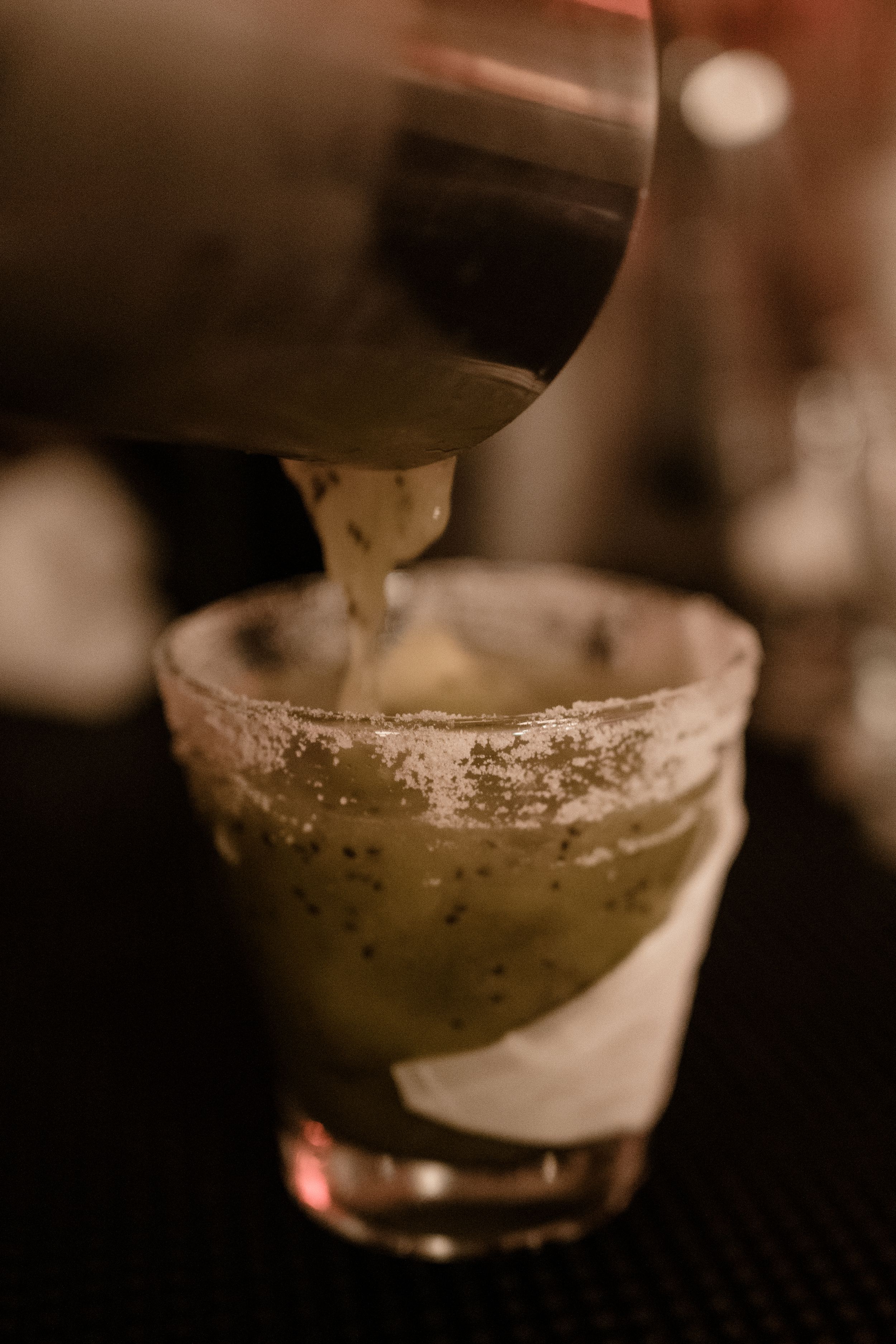 Close-up of a salt-rimmed cocktail glass on a dark surface.
