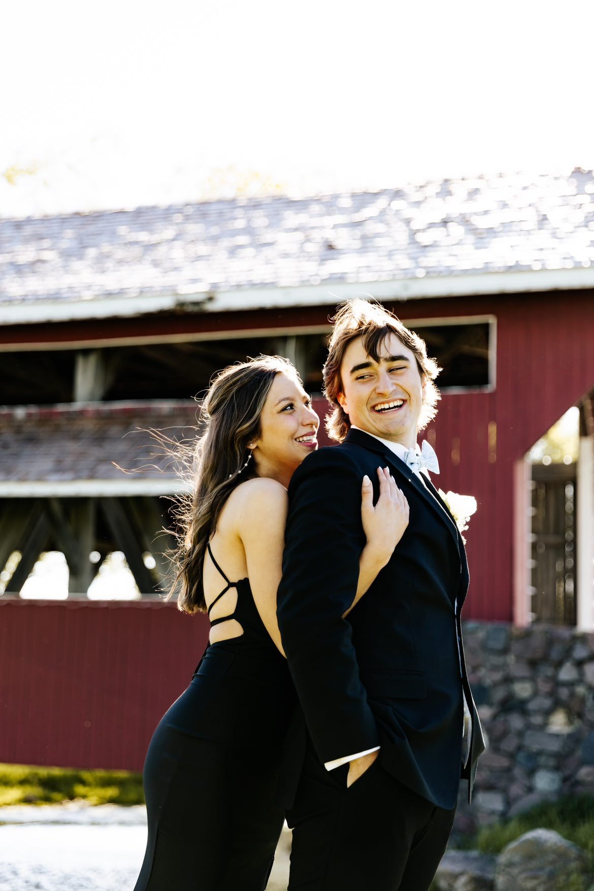 Two people in black outfits sharing joyful moments together outdoors.