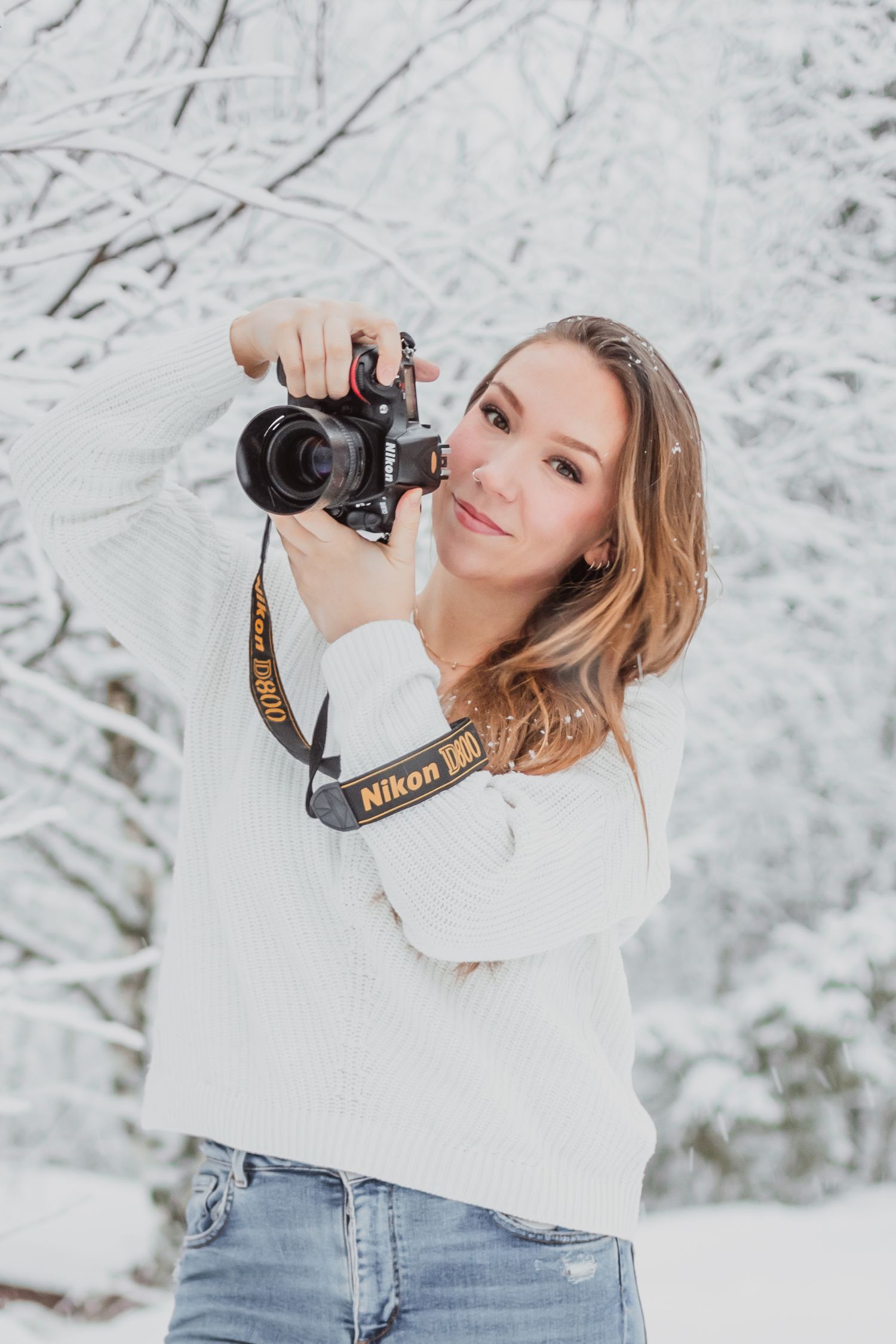 Playful outdoor portrait featuring white tank top and beige pants against natural foliage.