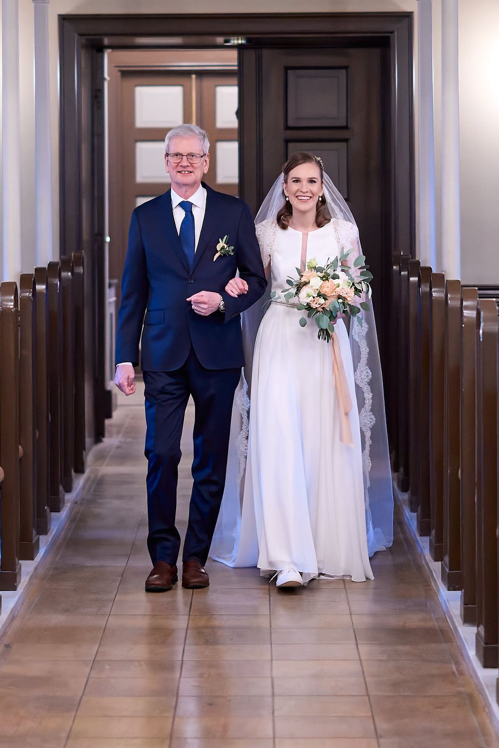 Wedding processional down church aisle with classic wooden pews.