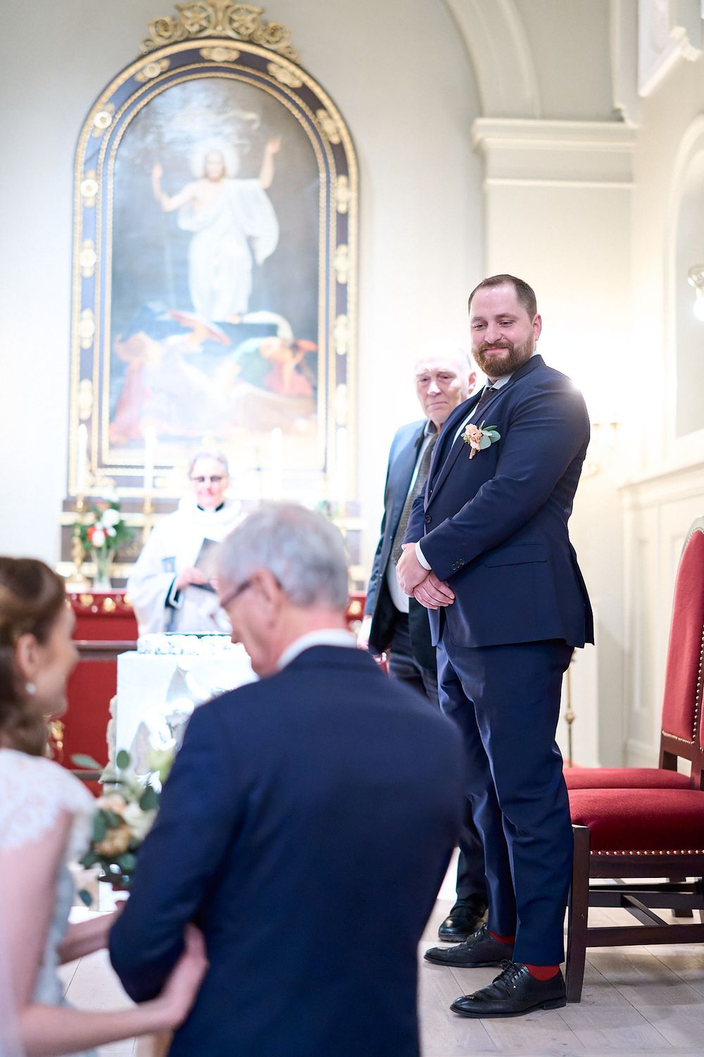 Church wedding scene with religious artwork and wedding party in formal attire.