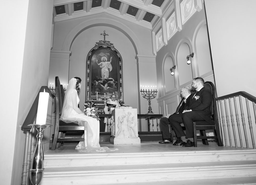 Black and white church ceremony photo with altar and religious symbols visible.