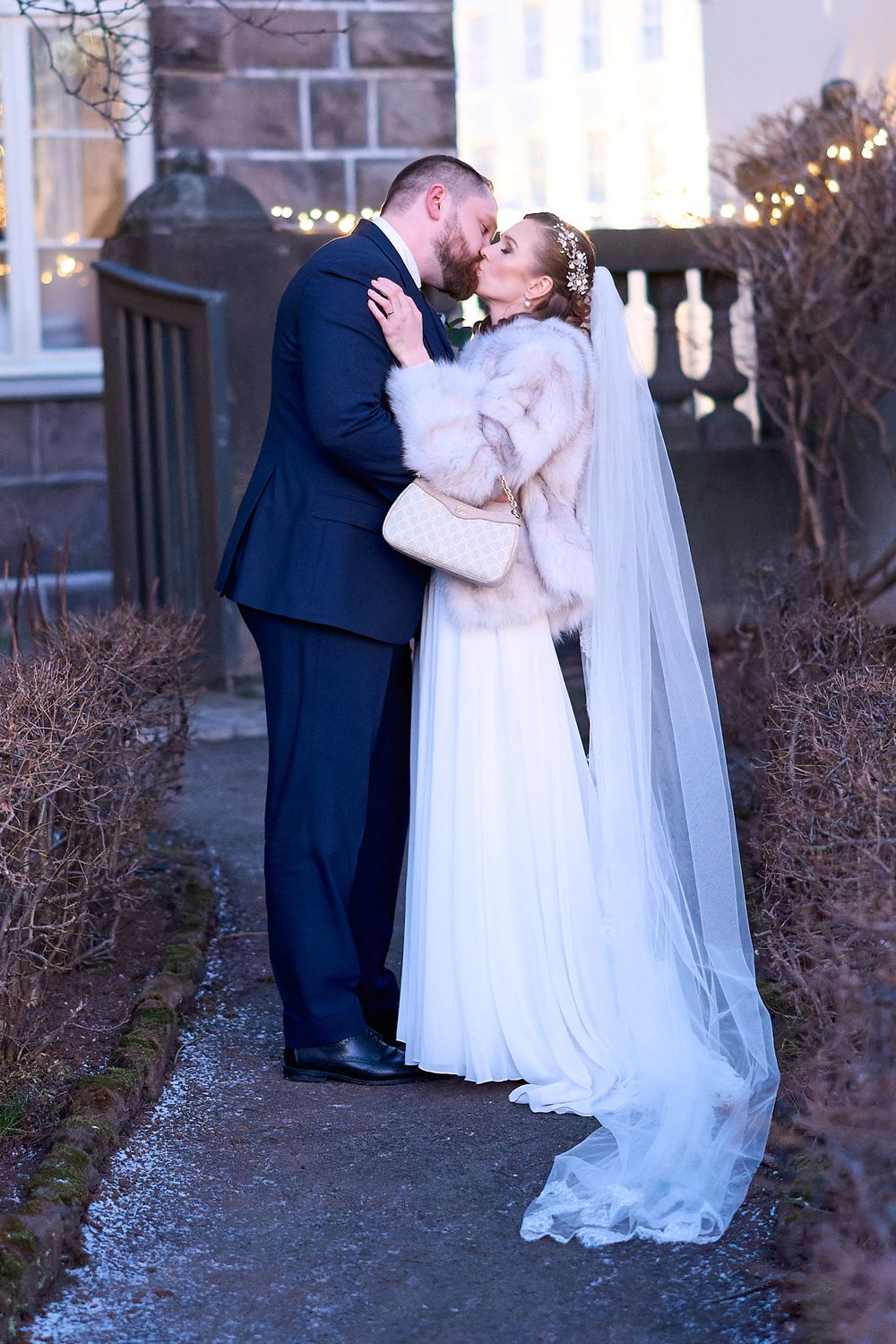 Romantic winter wedding portrait of couple embracing outdoors at dusk.
