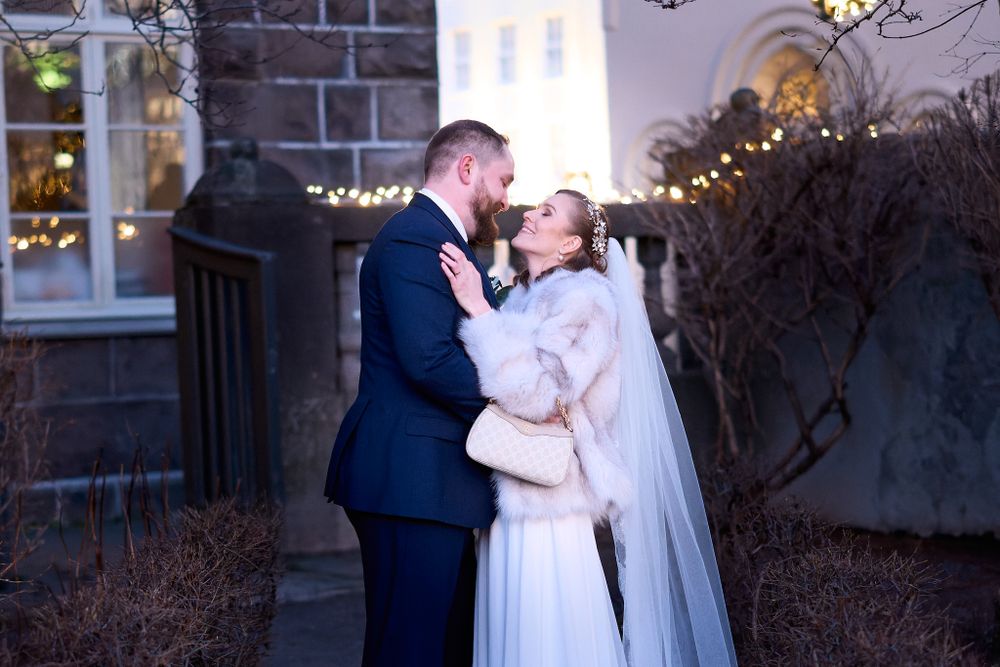 Evening wedding portrait of couple sharing intimate moment against brick building.