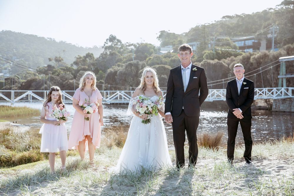 Wedding party walks along a scenic coastal path at sunset with mountains and ocean in the background.