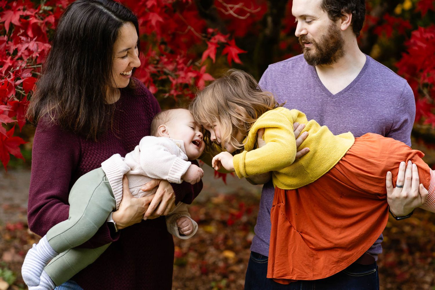 Sister kissing baby brother at a park in Seattle.