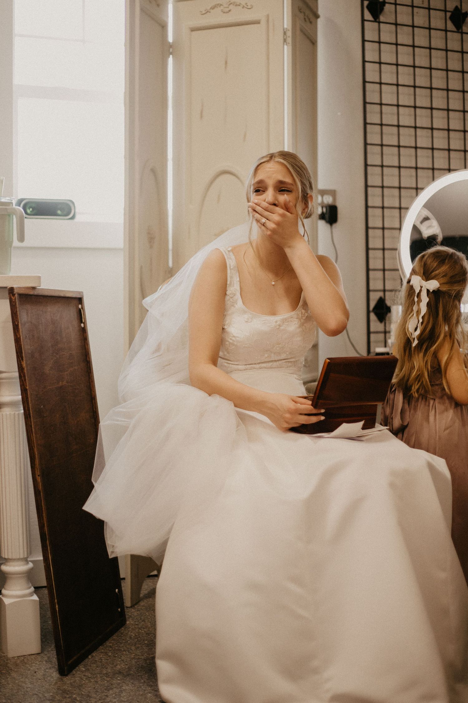 Candid moment of person in wedding dress showing emotional reaction while seated.