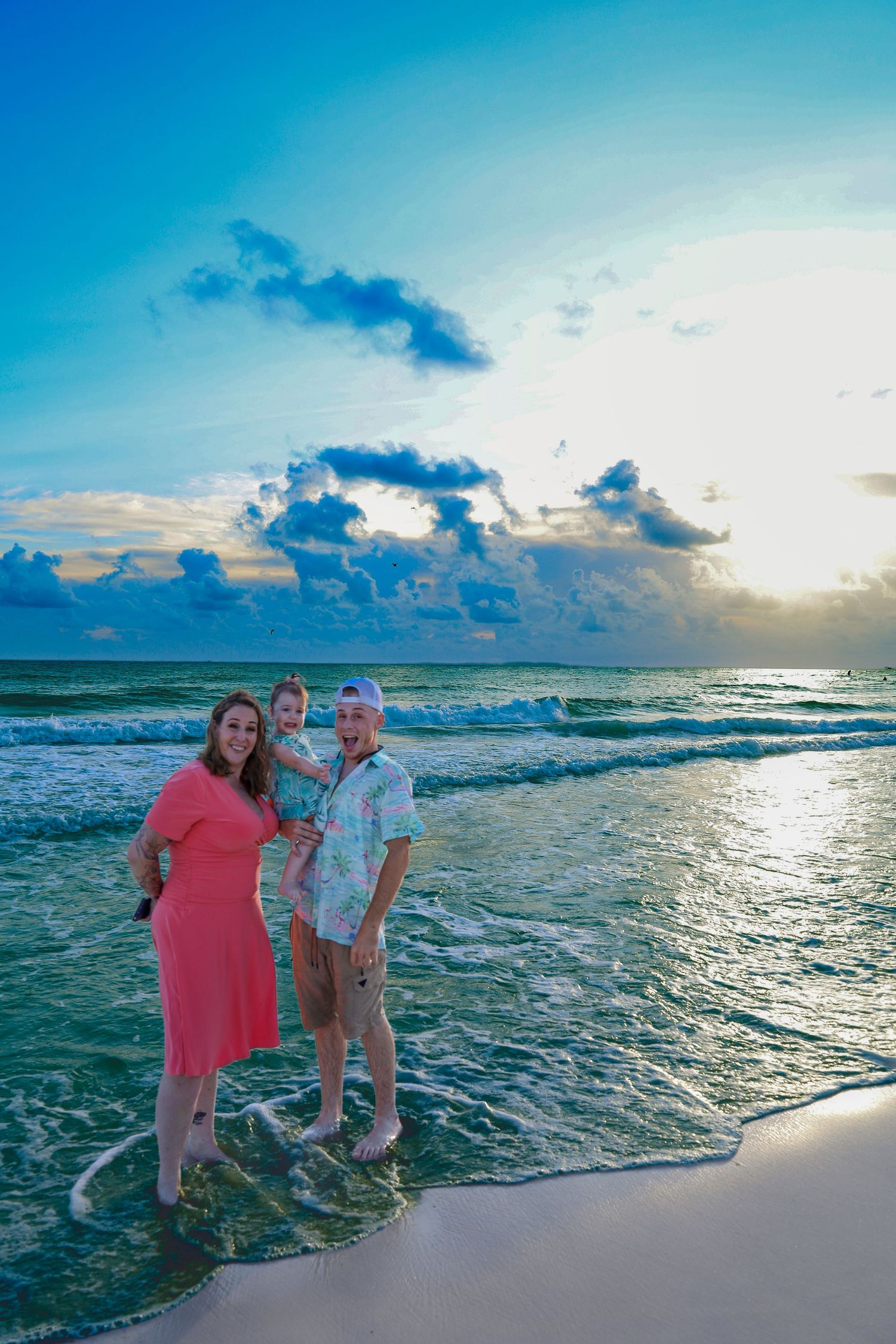 Beautiful turquoise ocean waves crash on white sandy beach at sunset with dramatic clouds in the sky.