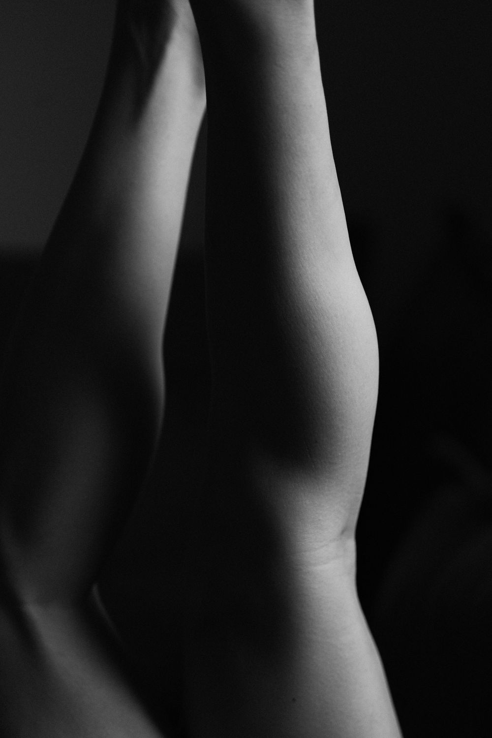 Abstract black and white photograph showing curved lines and shadows on skin.
