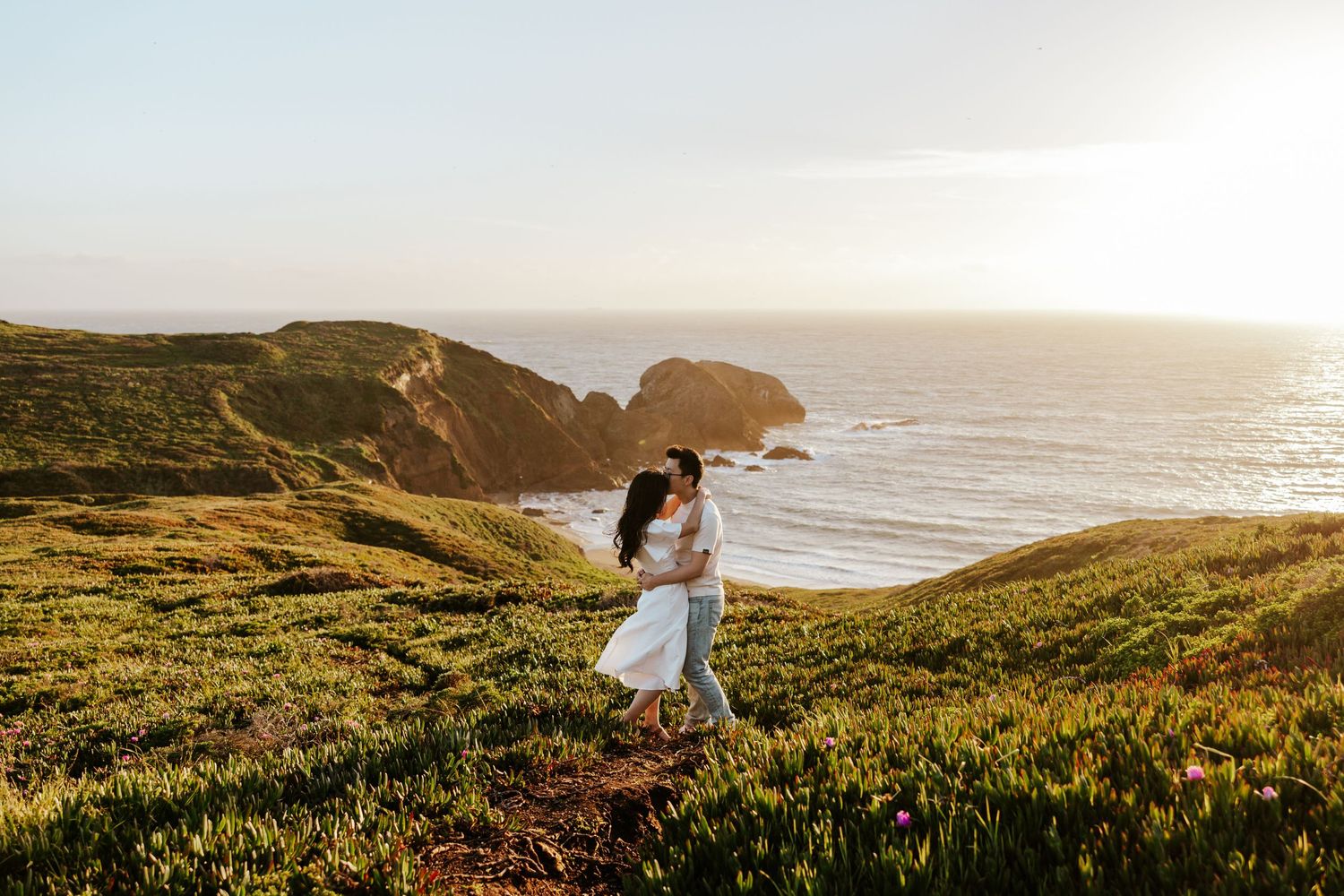 couple embracing each other in the north bay along the cliffs at sunset during their engagement photoshoot in the San Francisco Bay Area