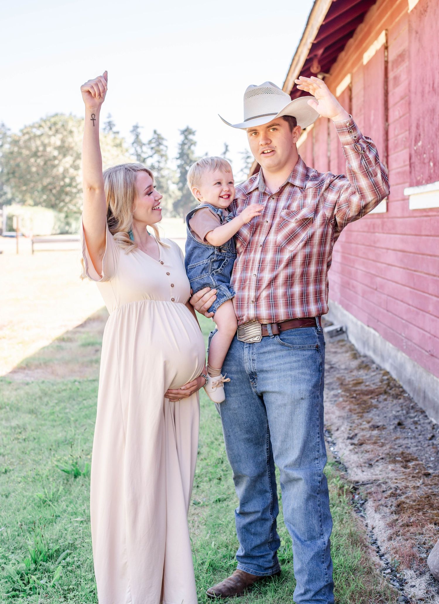 Family in western wear sharing joyful moments by vintage red barn.
