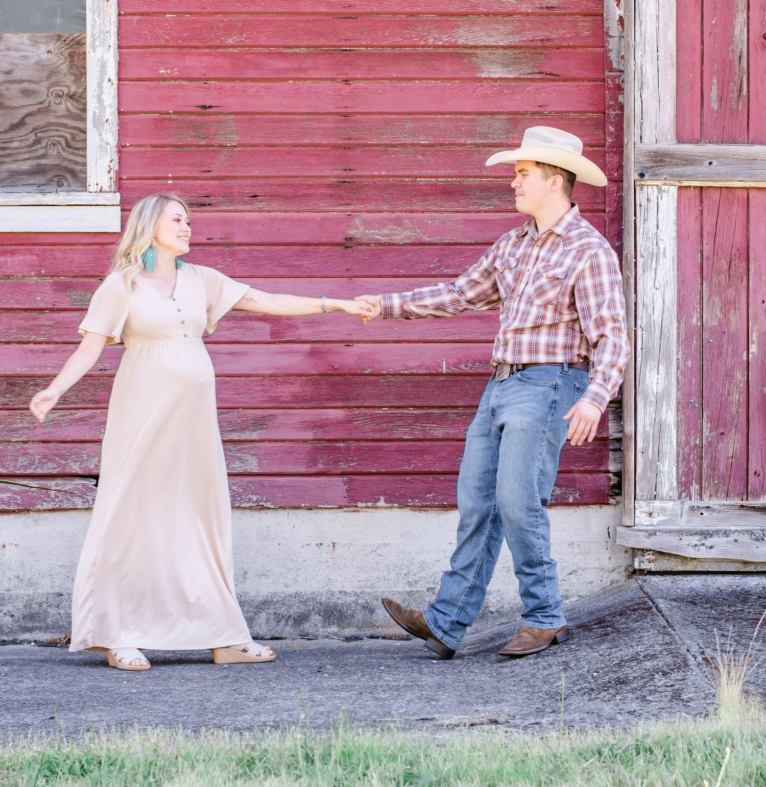 Family walking and playing together along rustic red barn exterior.