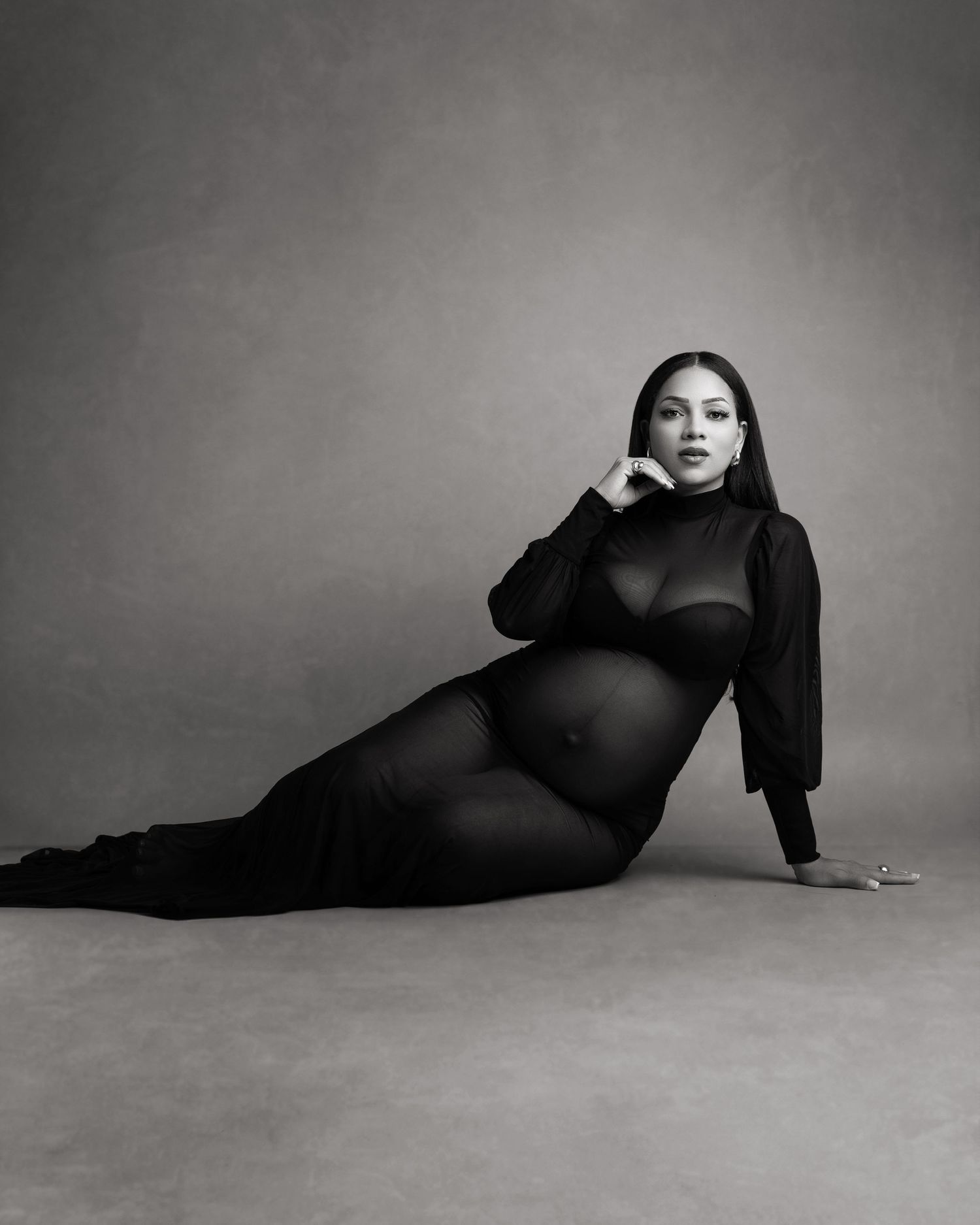 Black and white artistic maternity portraits showing elegant poses on studio floor.