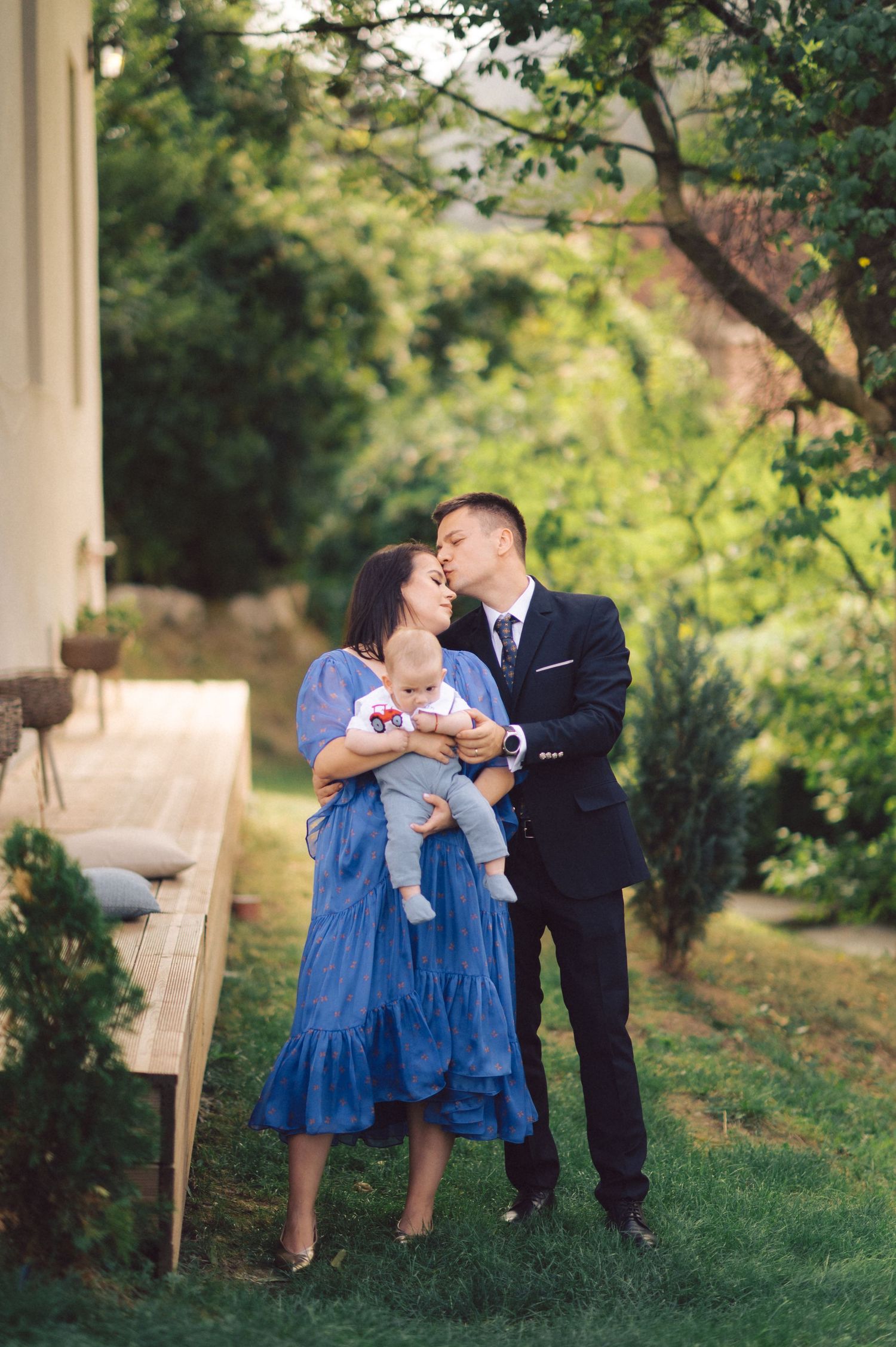 A tender family moment captured in a lush garden setting on a sunny day.