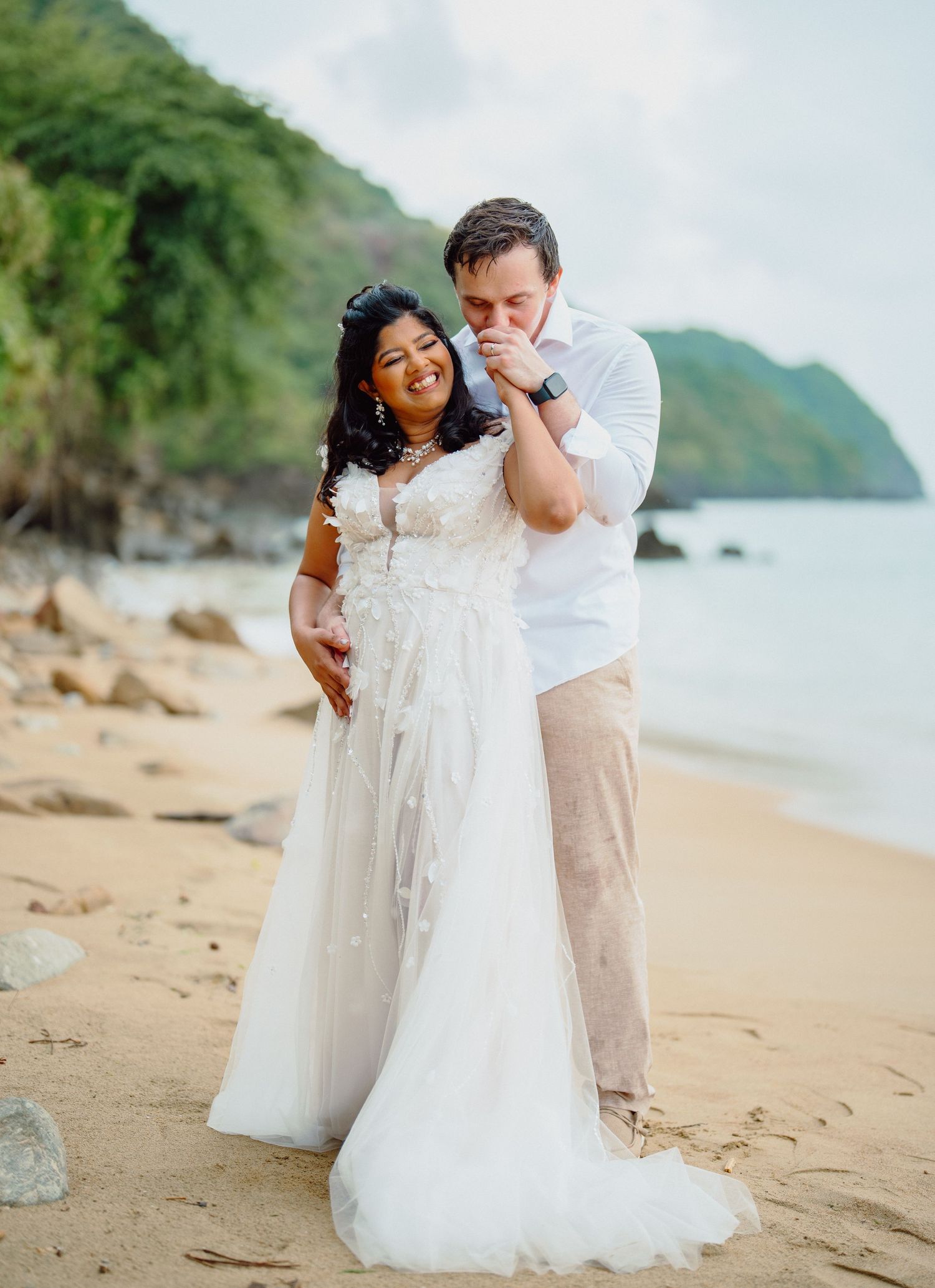 Romantic beachside wedding portrait with mountains in background.