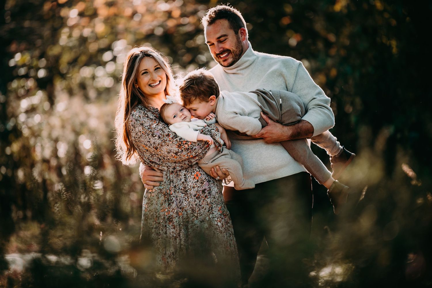 A joyful family moment captured in warm sunlight through trees.