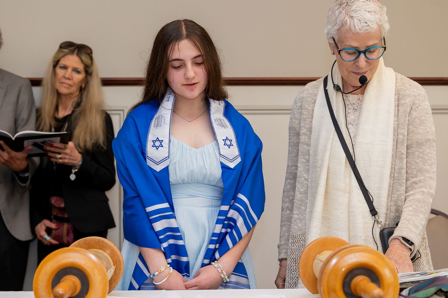 A traditional Torah reading ceremony with participants wearing prayer shawls and ceremonial attire.