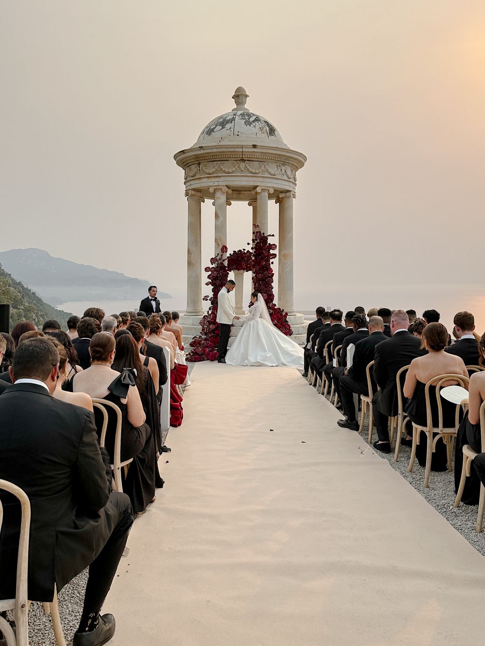 A beautiful outdoor wedding ceremony setup at Son Marroig in Mallorcaoverlooking a coastal landscape with a white gazebo and rows of chairs.