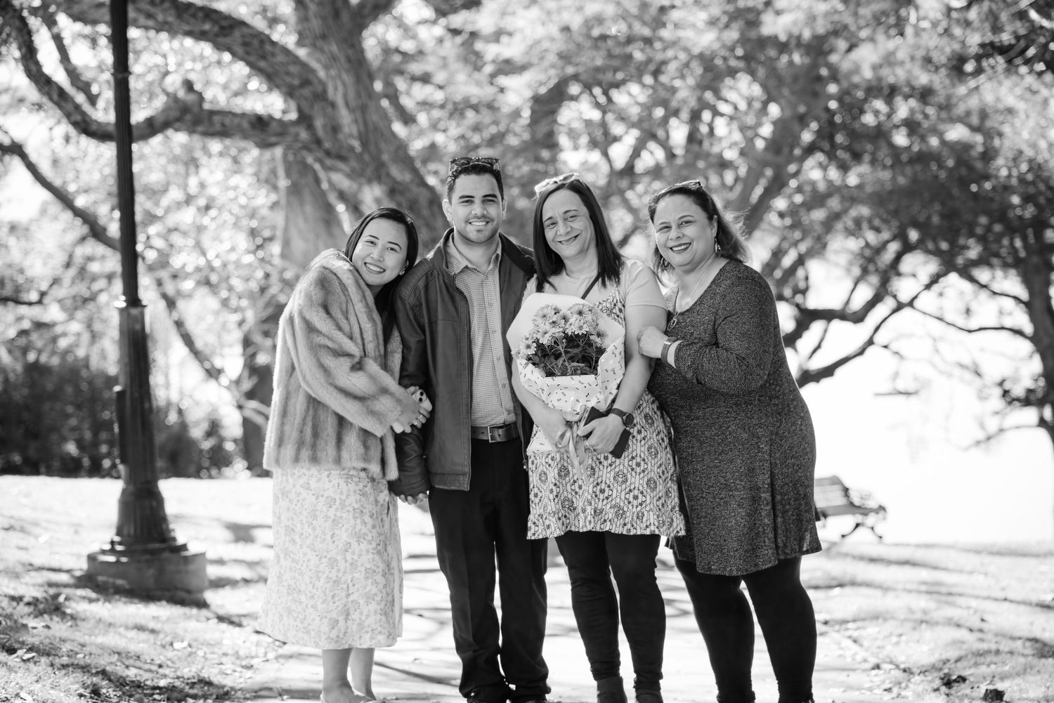 Black and white outdoor group portrait of family members together under trees.