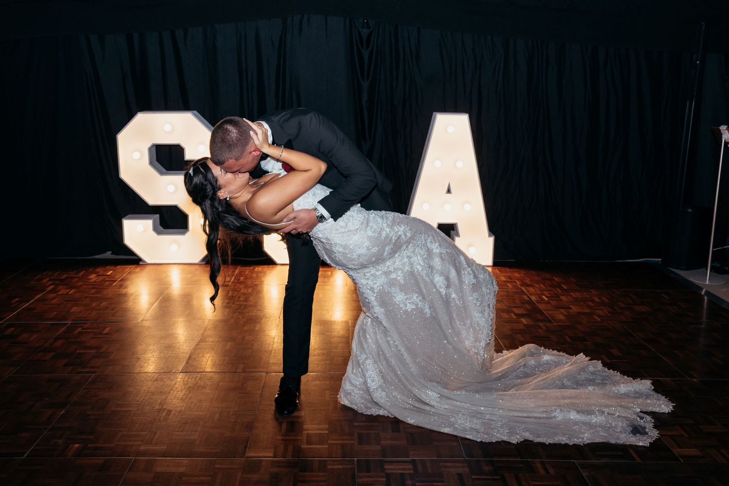 A romantic dance sequence shows a couple in formal attire performing a dramatic dip move on a dark stage.