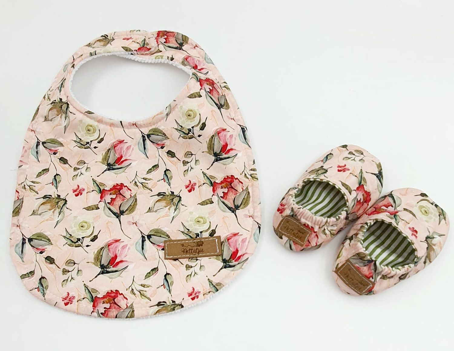 Pink floral baby shoes with green striped lining shown disassembled.