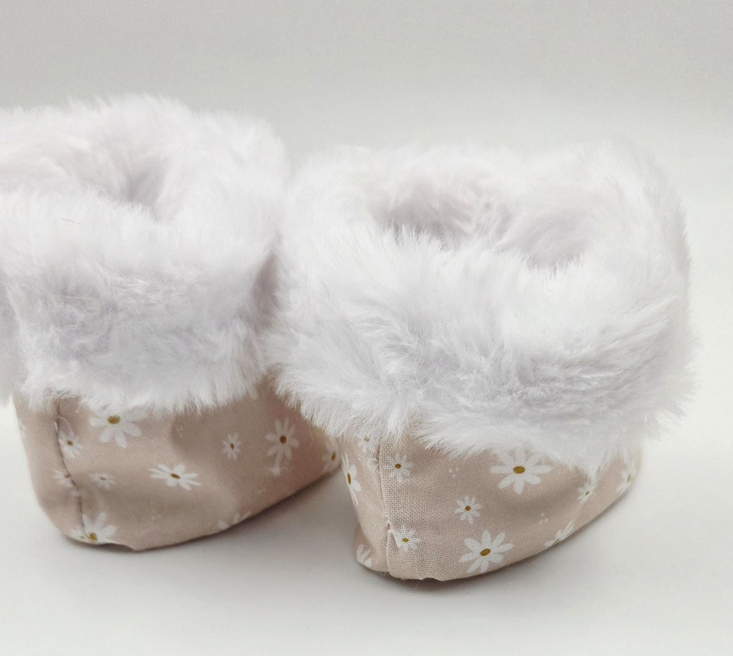 Pink floral baby booties with white faux fur trim, featuring daisy embroidery pattern.
