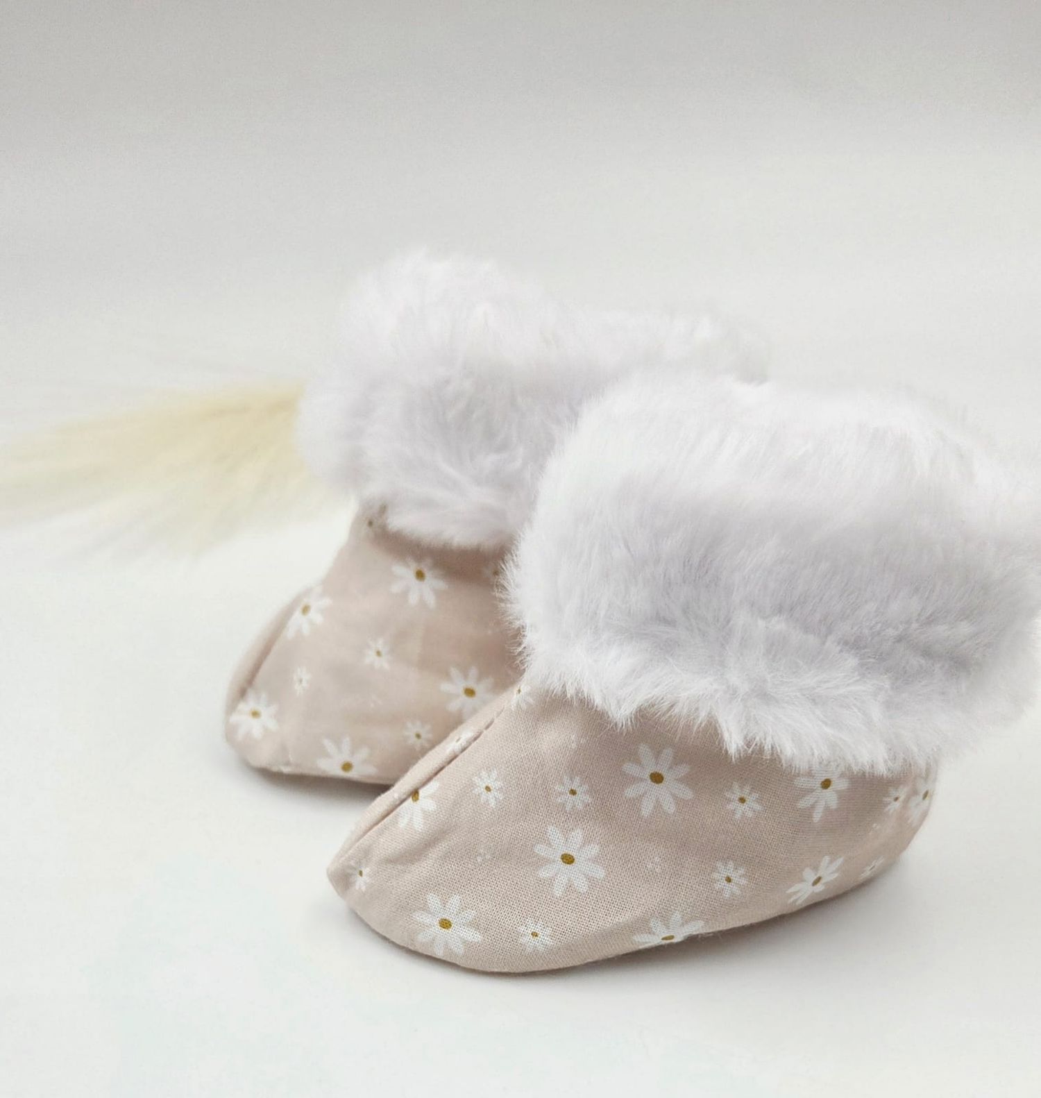 Soft pink daisy print baby booties with fluffy white faux fur cuff trim.