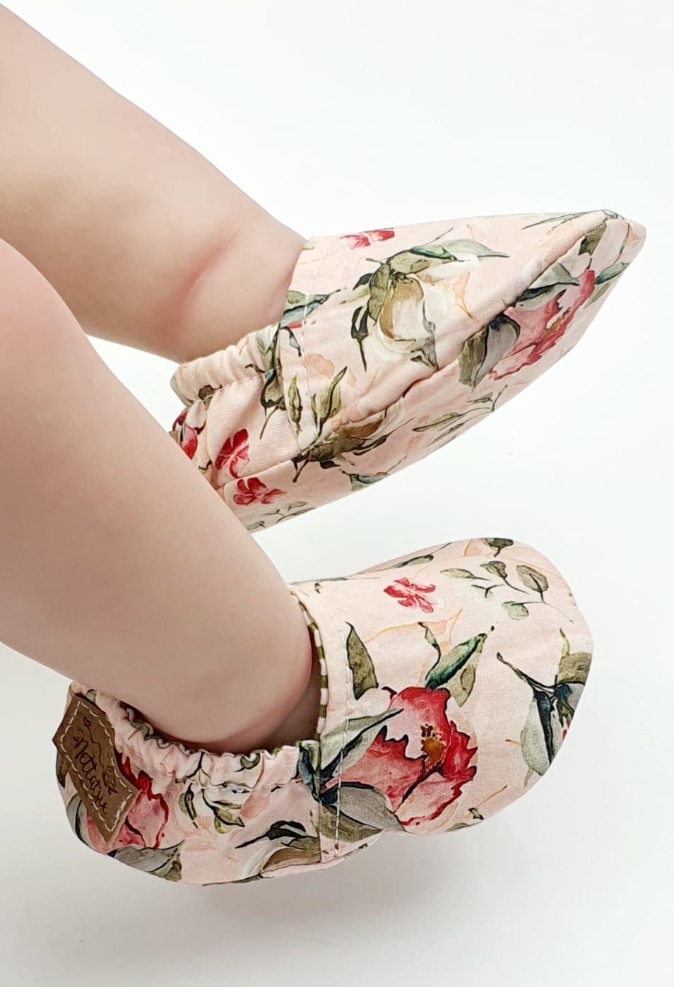 Demonstration of floral baby shoes being worn on infant feet.