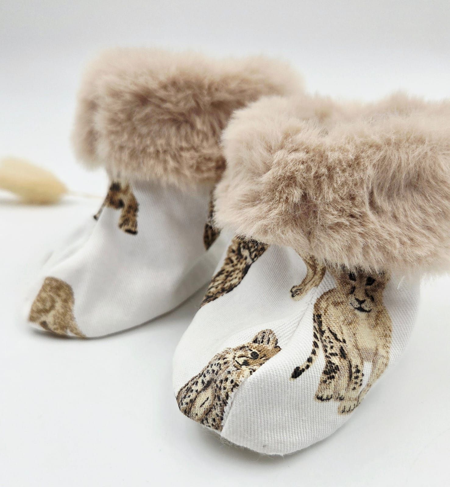 White baby booties with beige faux fur trim featuring leopard cheetah print pattern.