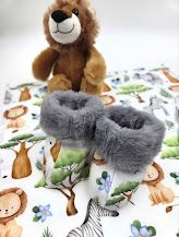 Baby booties with jungle animal print and gray faux fur trim displayed with a lion stuffed animal and safari-themed fabric.