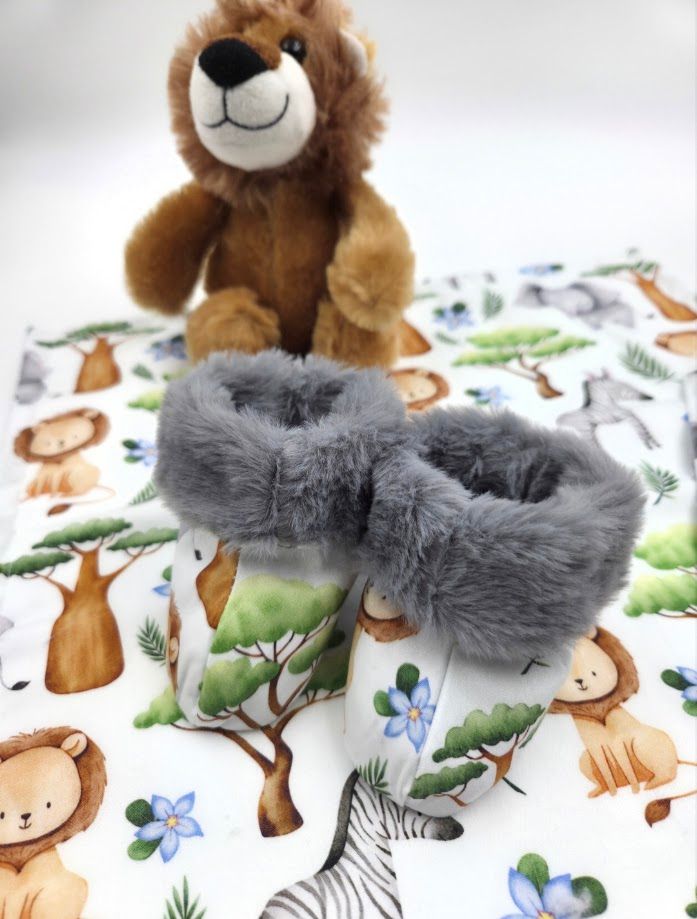 Gray faux fur baby booties displayed on safari animal print fabric with a plush lion toy in the background.