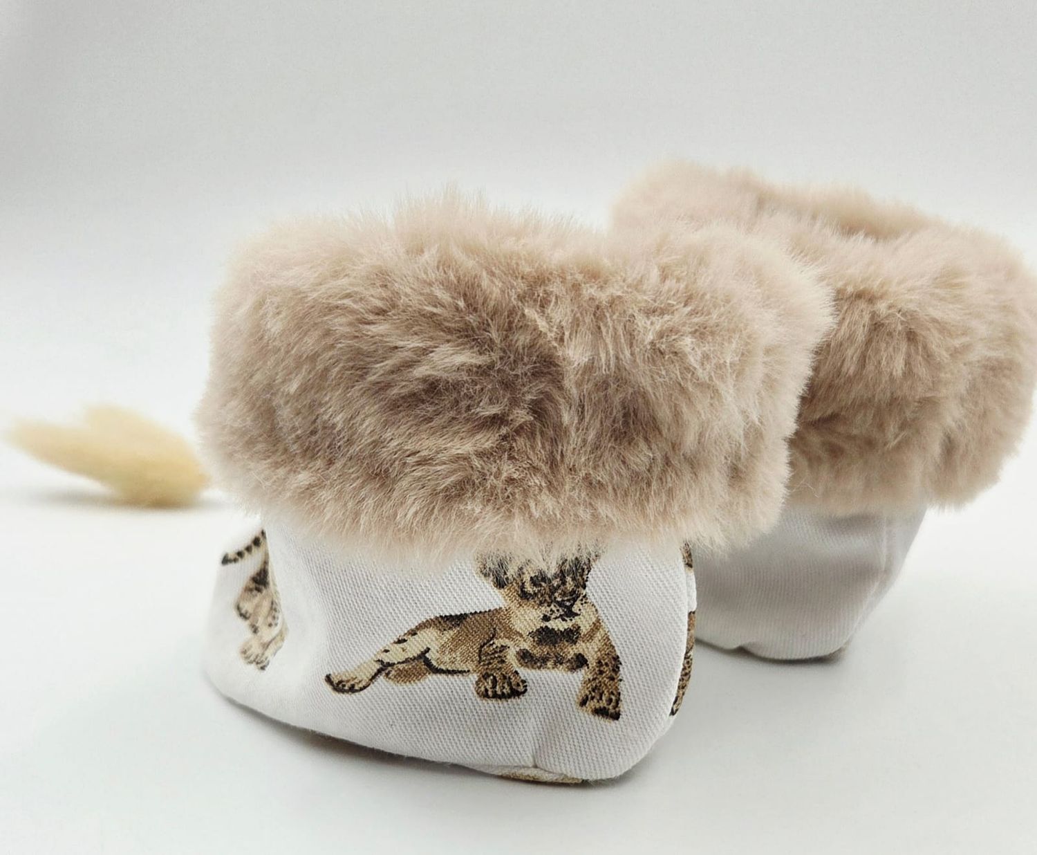 Adorable baby booties with fluffy fur trim and cat print fabric, perfect for keeping tiny feet warm and stylish.