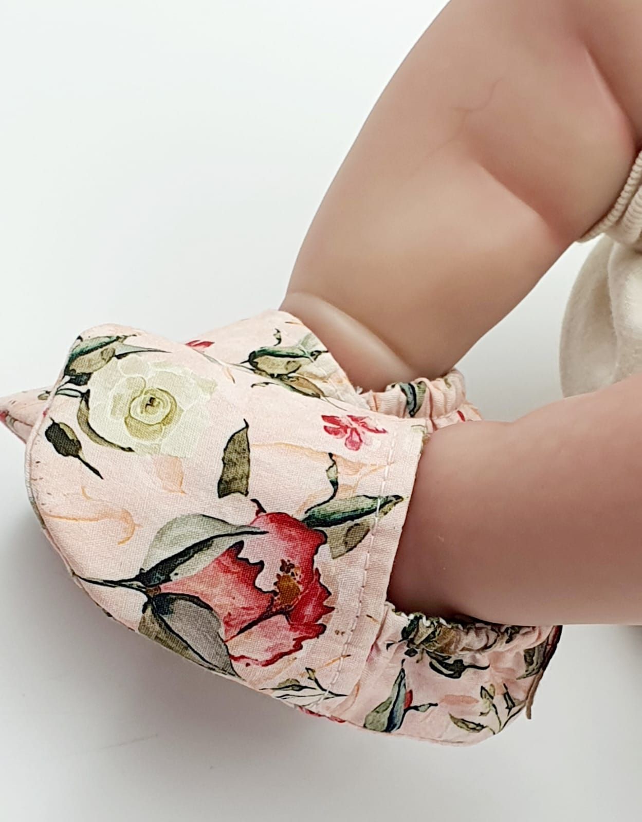 Hands folding pink floral patterned fabric against white background.