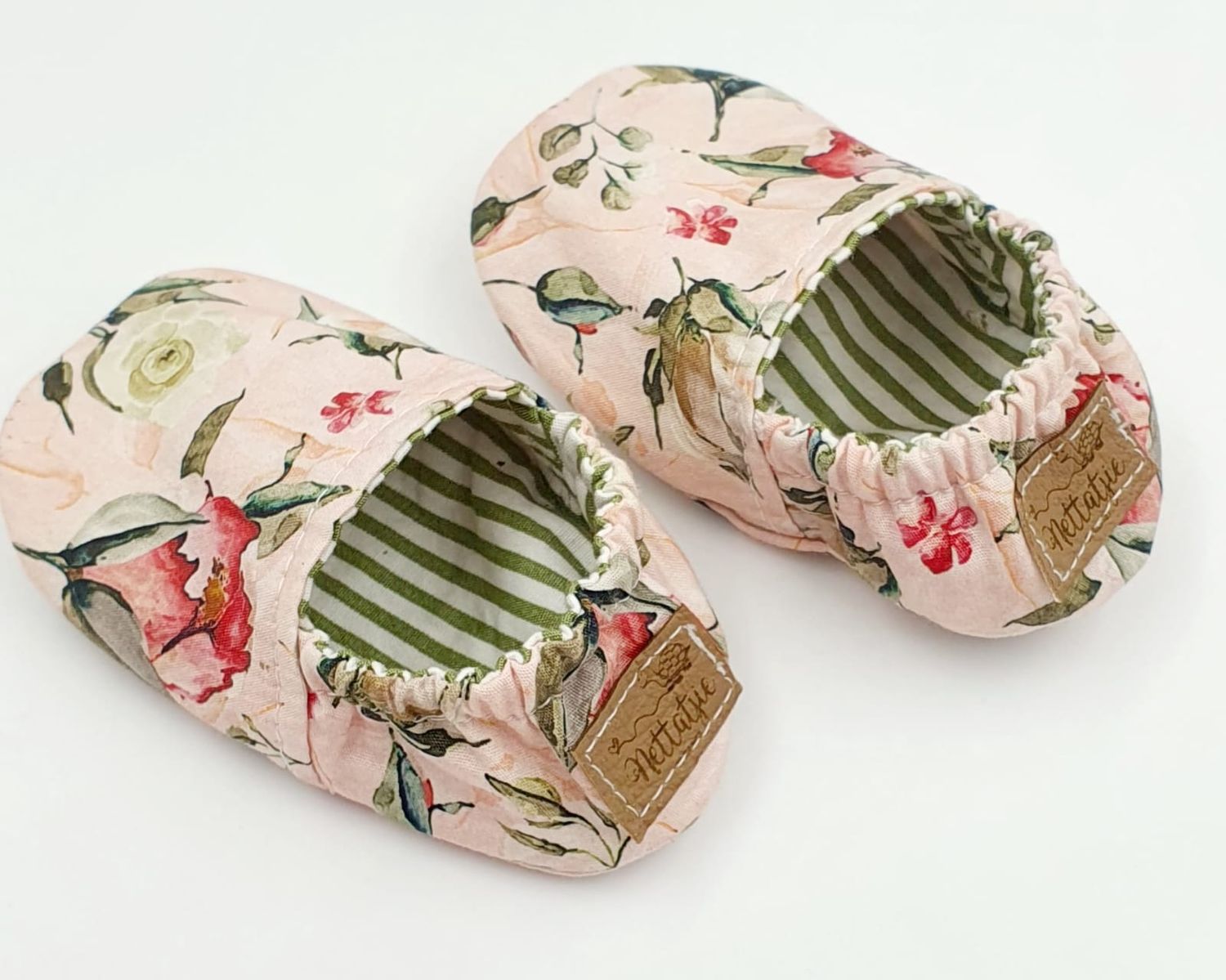 Pink floral fabric rolls with striped lining displayed in a row.