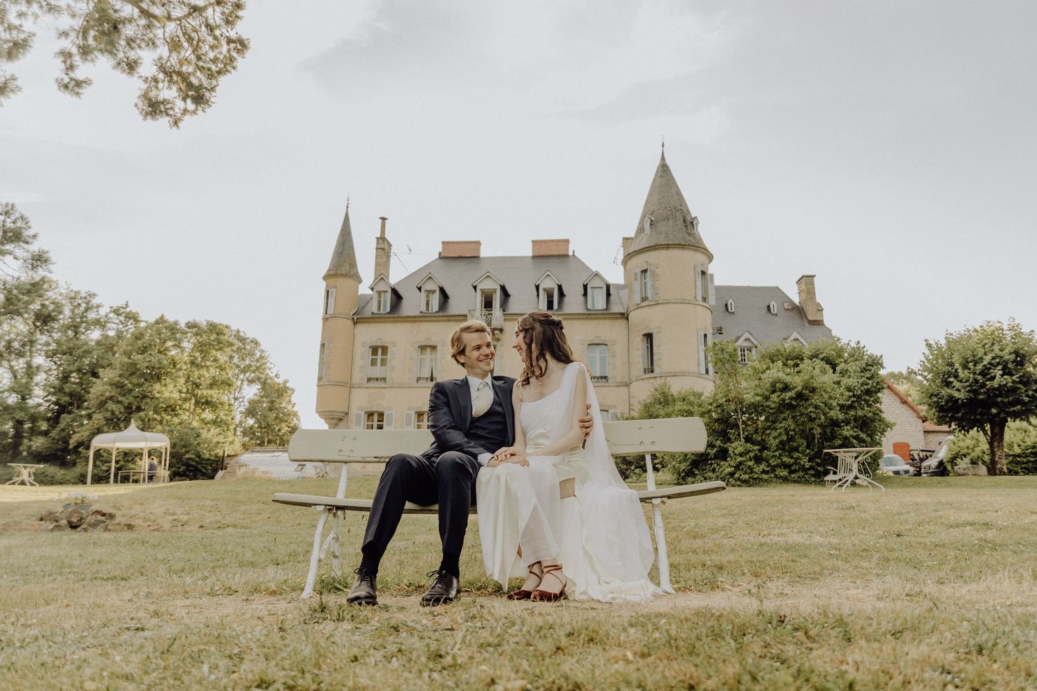 A romantic couple celebrates their wedding day with a joyful dance on a sprawling lawn in front of a majestic French chateau.