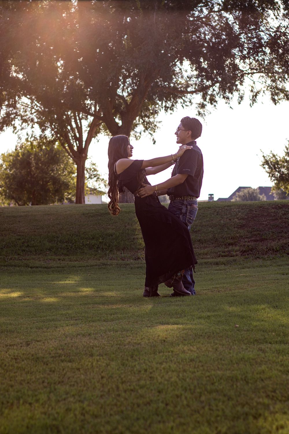 Couple sits together on grassy hill during sunset photo session.