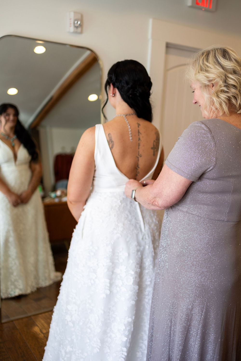 Mother zipping up daughter's wedding dress on her wedding day