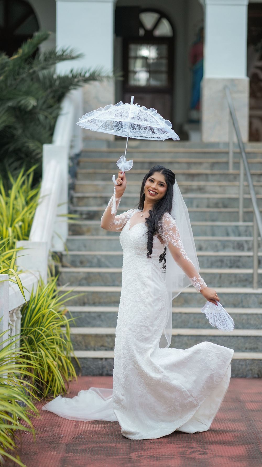 Bride in a white wedding dress holding an umbrella outdoors