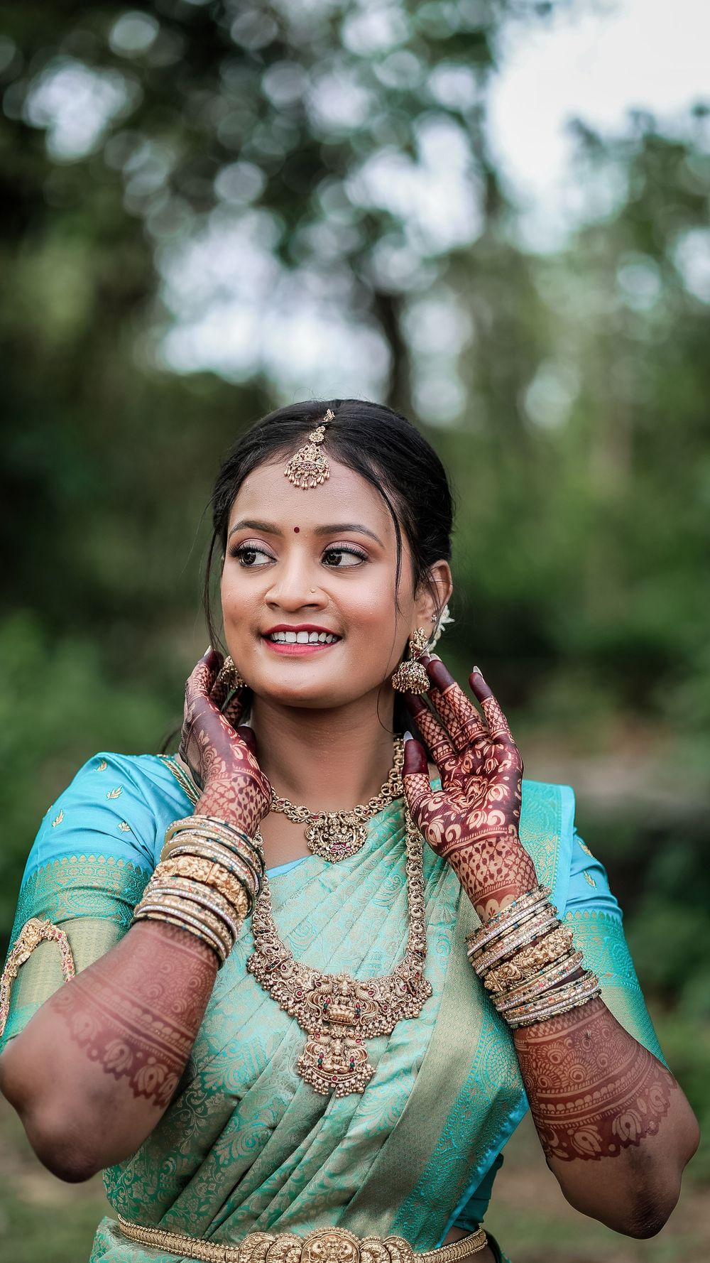 Woman wearing a traditional green sari and jewelry in an outdoor portrait