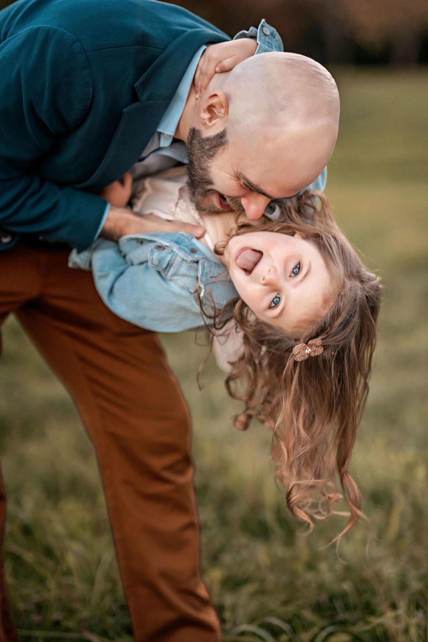 A tender candid moment between parent and child playing outdoors with joyful expressions in golden sunlight.