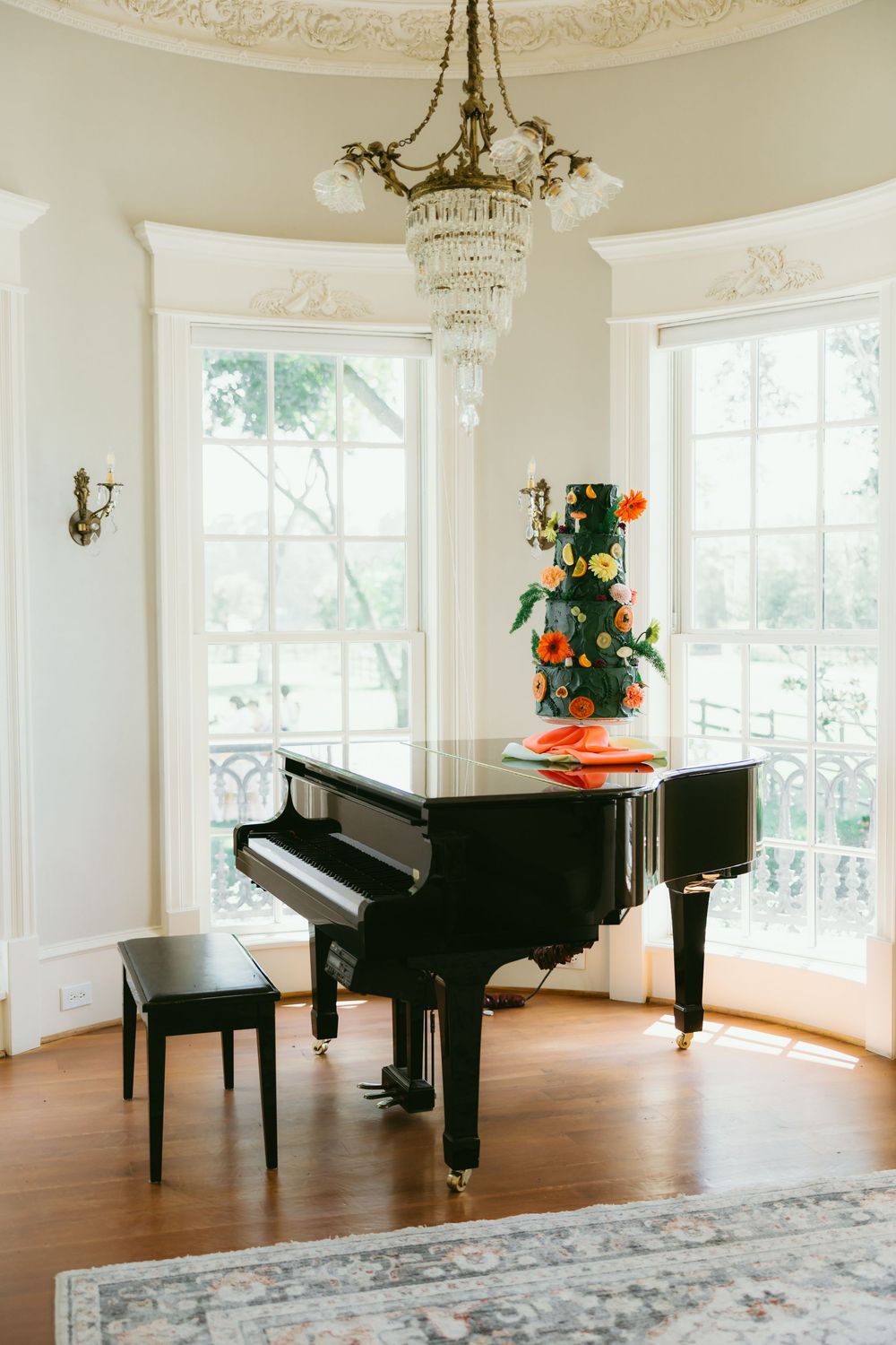Elegant music room with grand pianos and ornate ceiling details in a bright white space with hardwood floors.