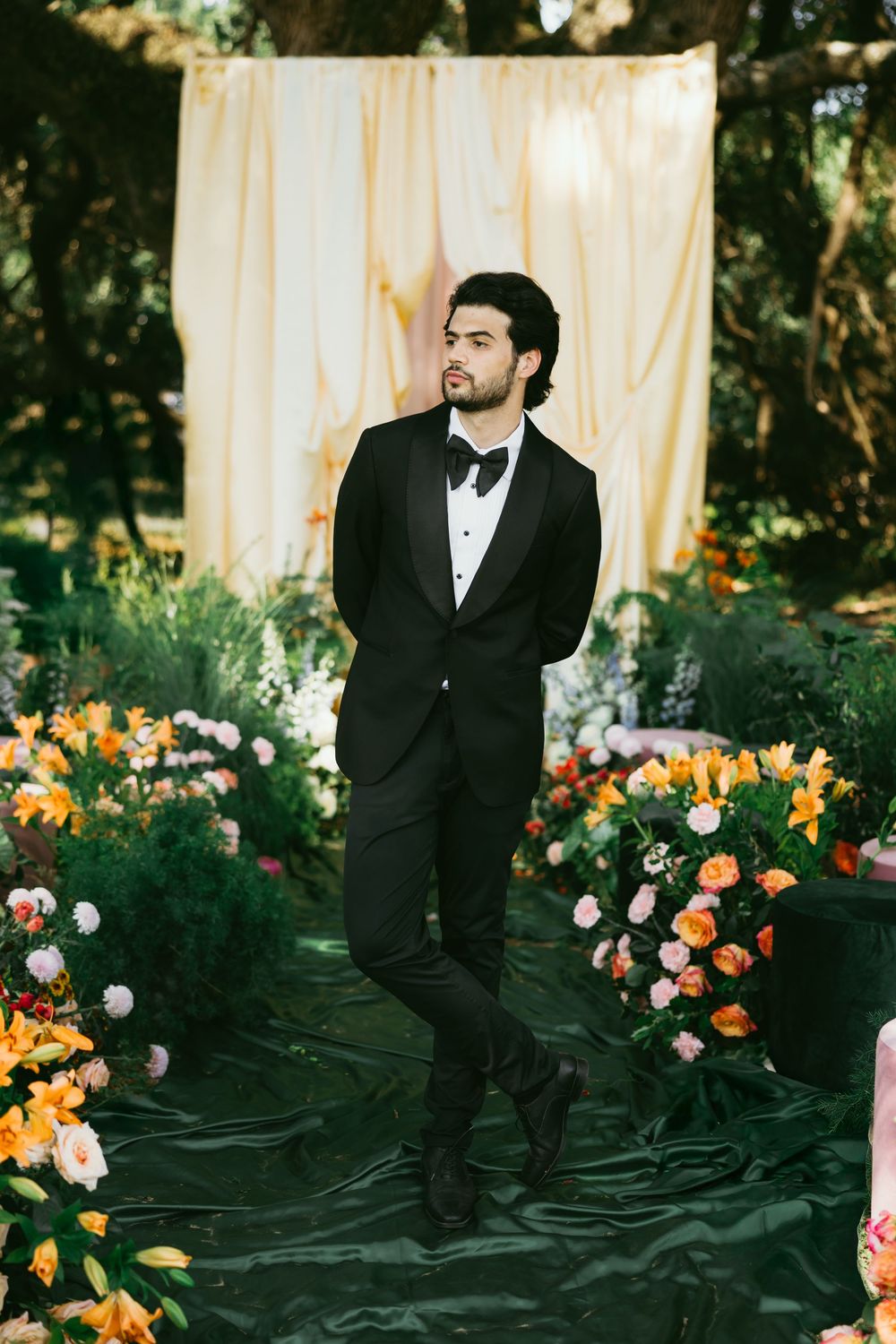 A wedding scene with orange and peach floral arrangements against a light backdrop in an outdoor garden setting.