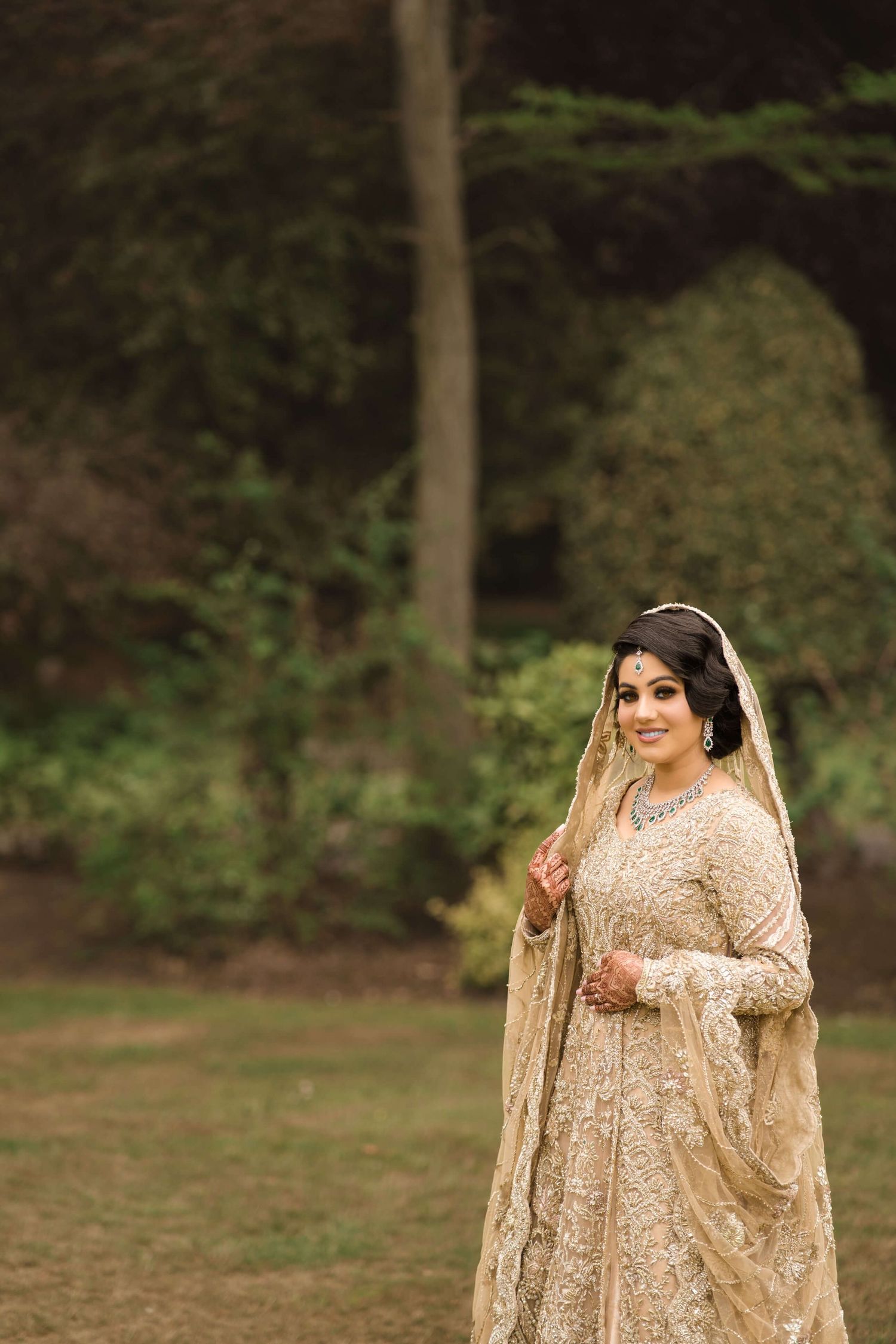 newly wedded wife posing after holy matrimony smiling blissfully towards the camera, wearing a golden Lehenga