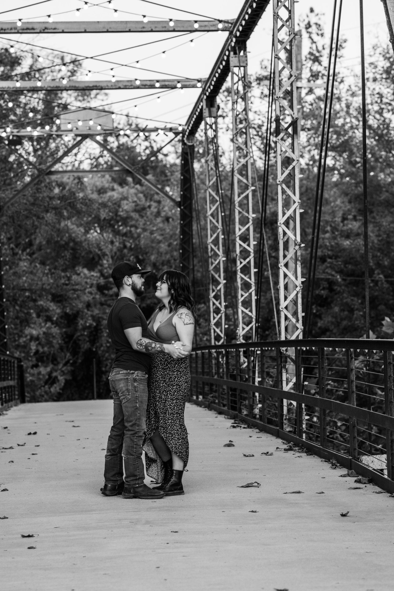 Close-up of engagement ring while couple shares romantic kiss at sunset.