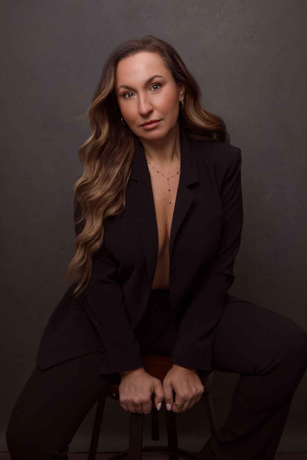Dramatic portrait series in black blazer against dark background with moody lighting.