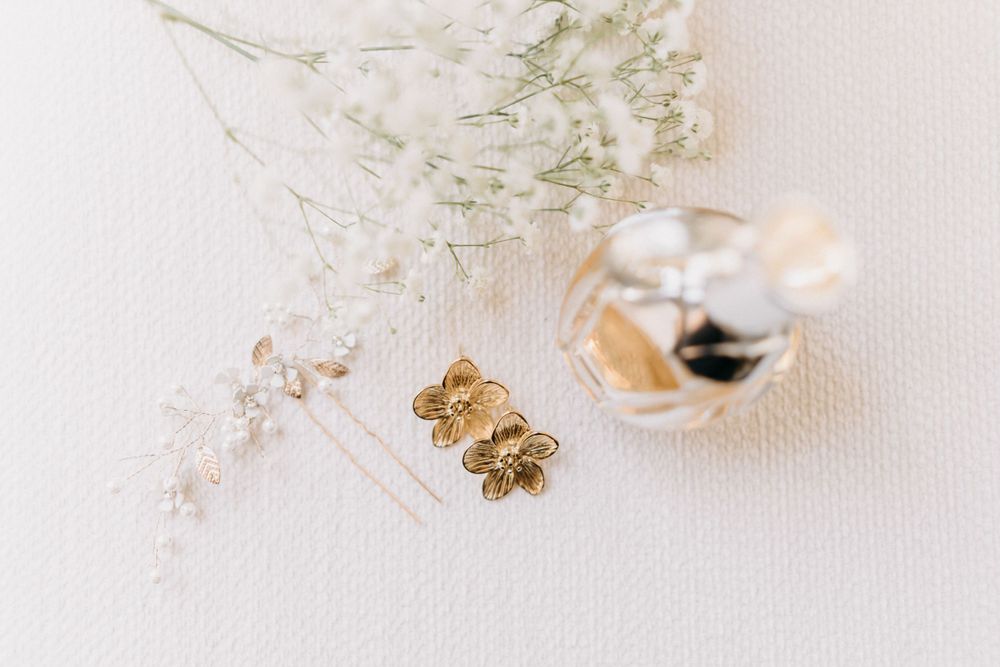 Gold wedding rings and baby's breath flowers arranged on white surface with soft natural lighting.
