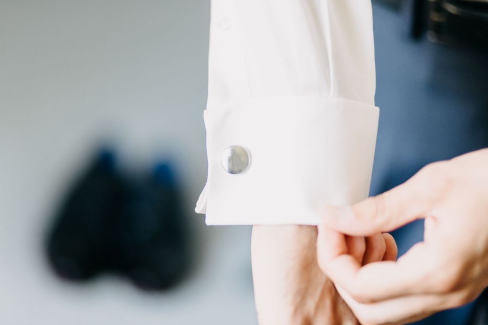Close-up detail shot of a white dress shirt cuff and button.