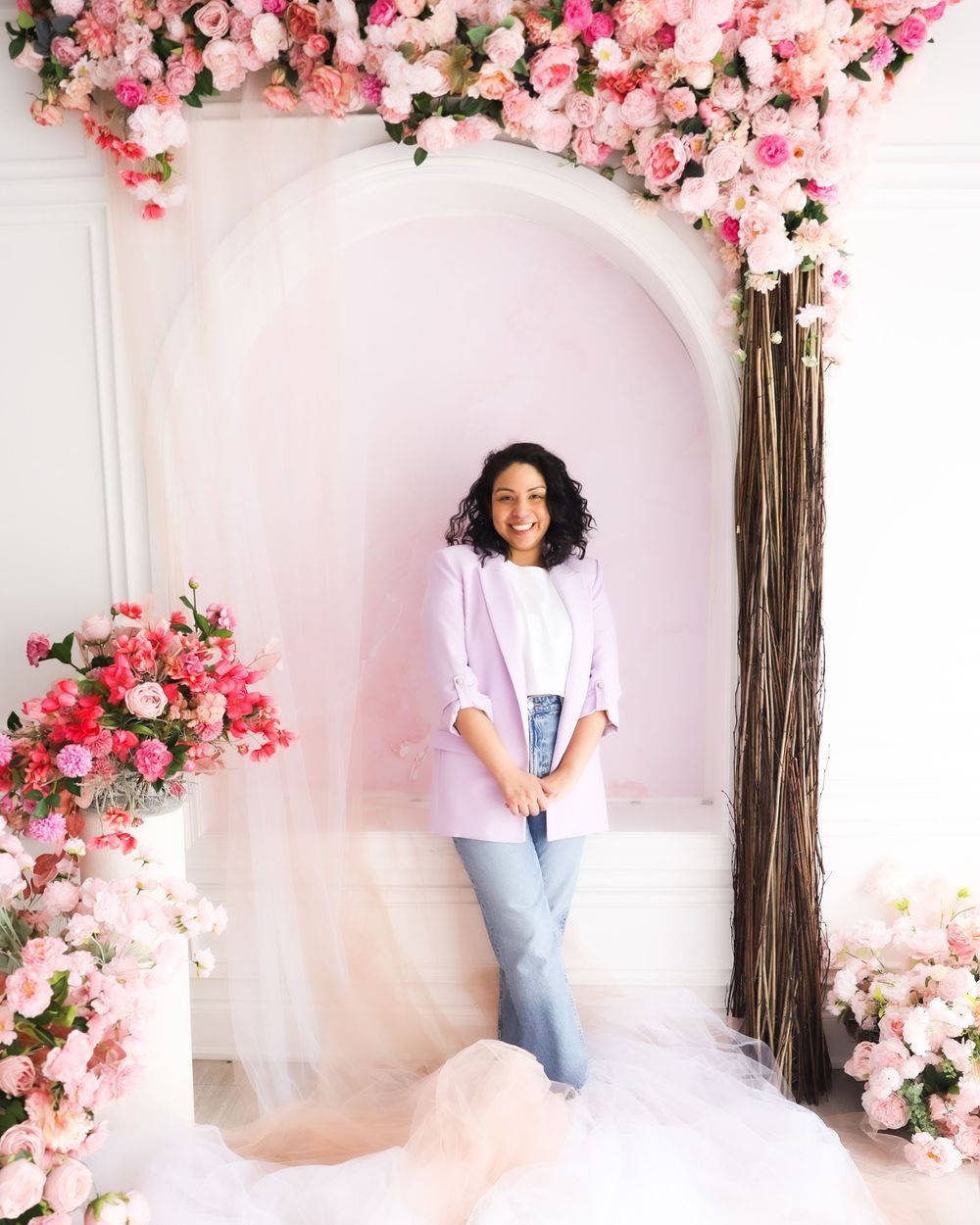 Portrait in white archway decorated with cascading pink floral arrangements.